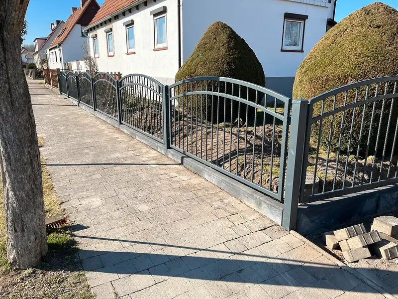 Schmuckzaun mit Bögen auf einem Sockel entlang der Straße