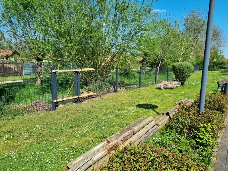 Sonniger Garten im Frühling, ein neuer Doppelstabmattenzaun wird gesetzt